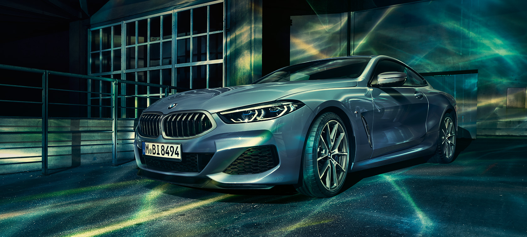 A three-quarter front still shot of the BMW 8 Series Coupé in an urban setting.