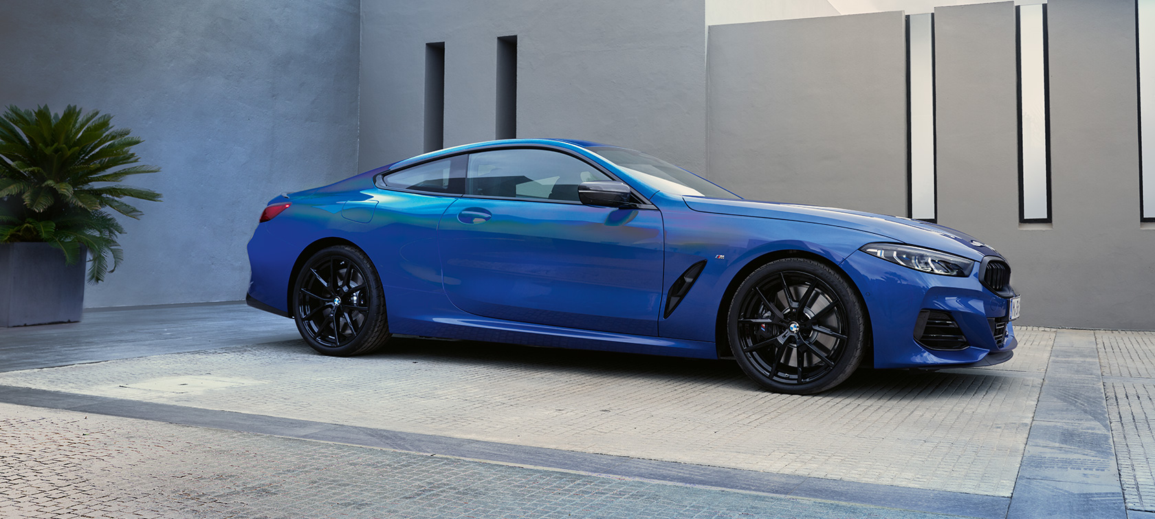 BMW M850i xDrive Coupé, G15, LCI, atualização, 2022, pintura azul Portimao M metalizada, perspetiva lateral a três quartos, parado em frente a um edifício